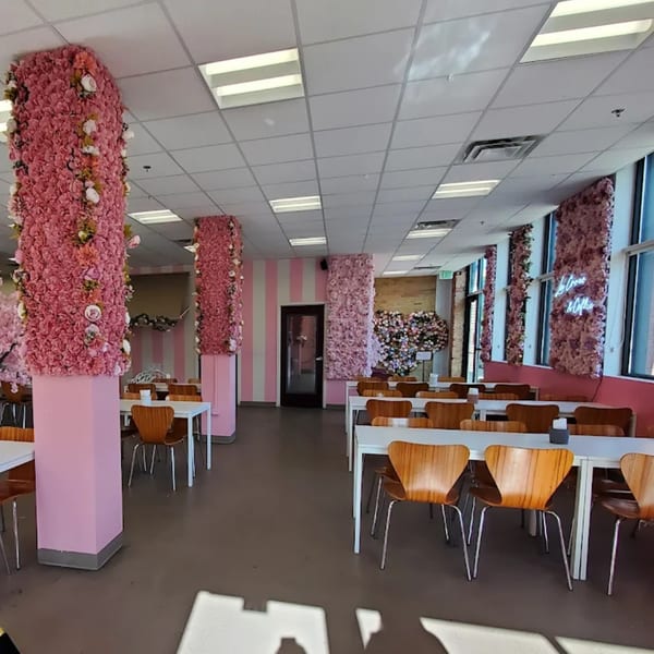 La Crepe Og Gourmet's dining room with pink floral pillars, white tables, and wooden chairs.