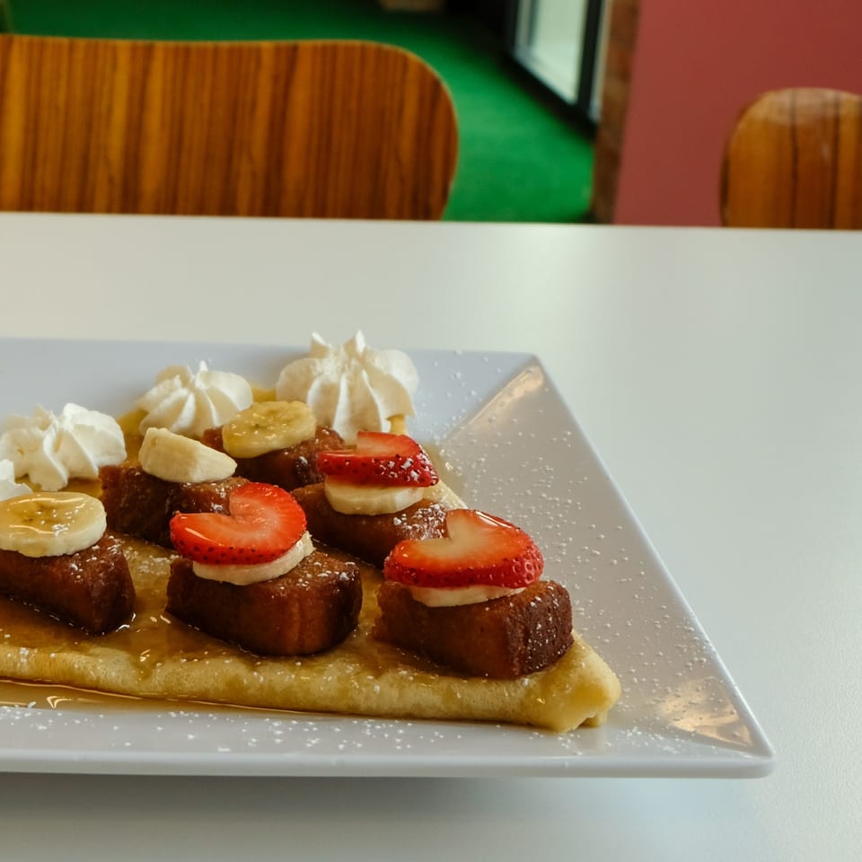 La Crepe Og Gourmet's crepe topped with French toast bites, strawberries, bananas, and whipped cream.